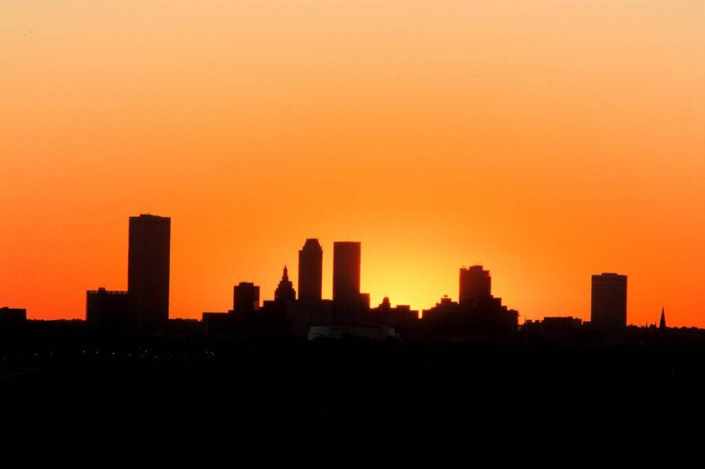 Silhouette of a city skyline against an orange sunset