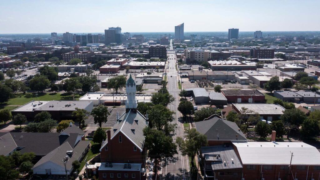 Aerial view of a cityscape featuring buildings, streets, and trees.