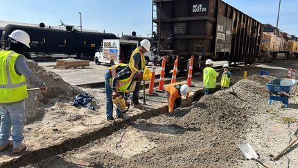 Person using a pencil to mark a floor tile for cutting near a door frame.
