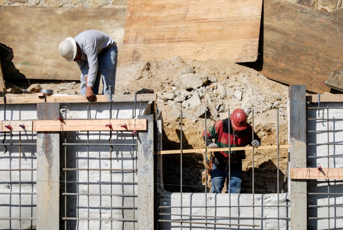 Construction workers installing rebar for a concrete structure, outdoors.