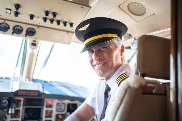 A pilot is smiling while sitting in the cockpit of an airplane.