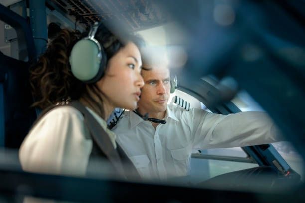 A man and a woman wearing headphones are sitting in a car.