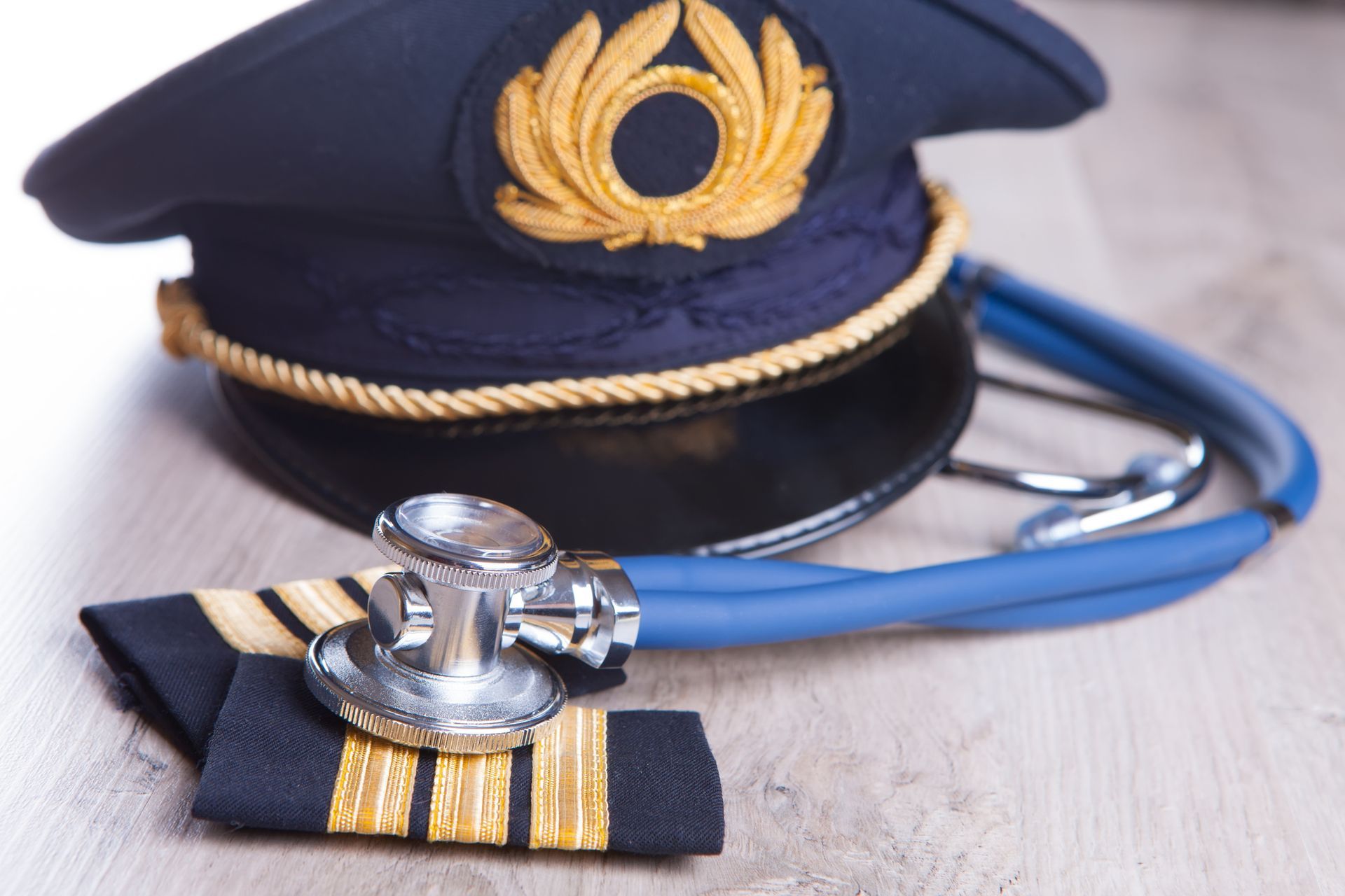 Navy captain's hat, epaulettes, and stethoscope, suggesting medical maritime service on a wooden surface.