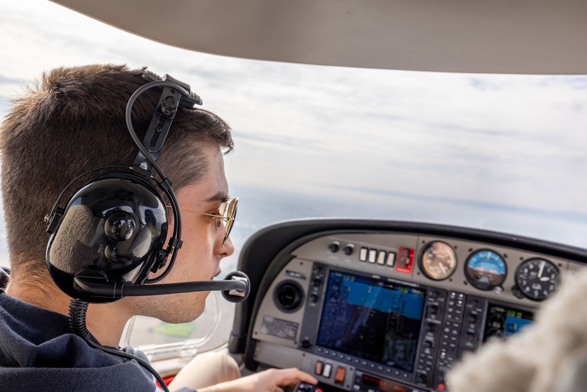 A man wearing headphones is sitting in the cockpit of an airplane. A man wearing headphones is sitting in the cockpit of an airplane.
