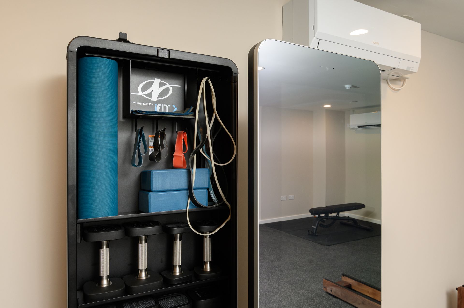 A gym with a mirror and a shelf with dumbbells and a yoga mat at Walton Court.