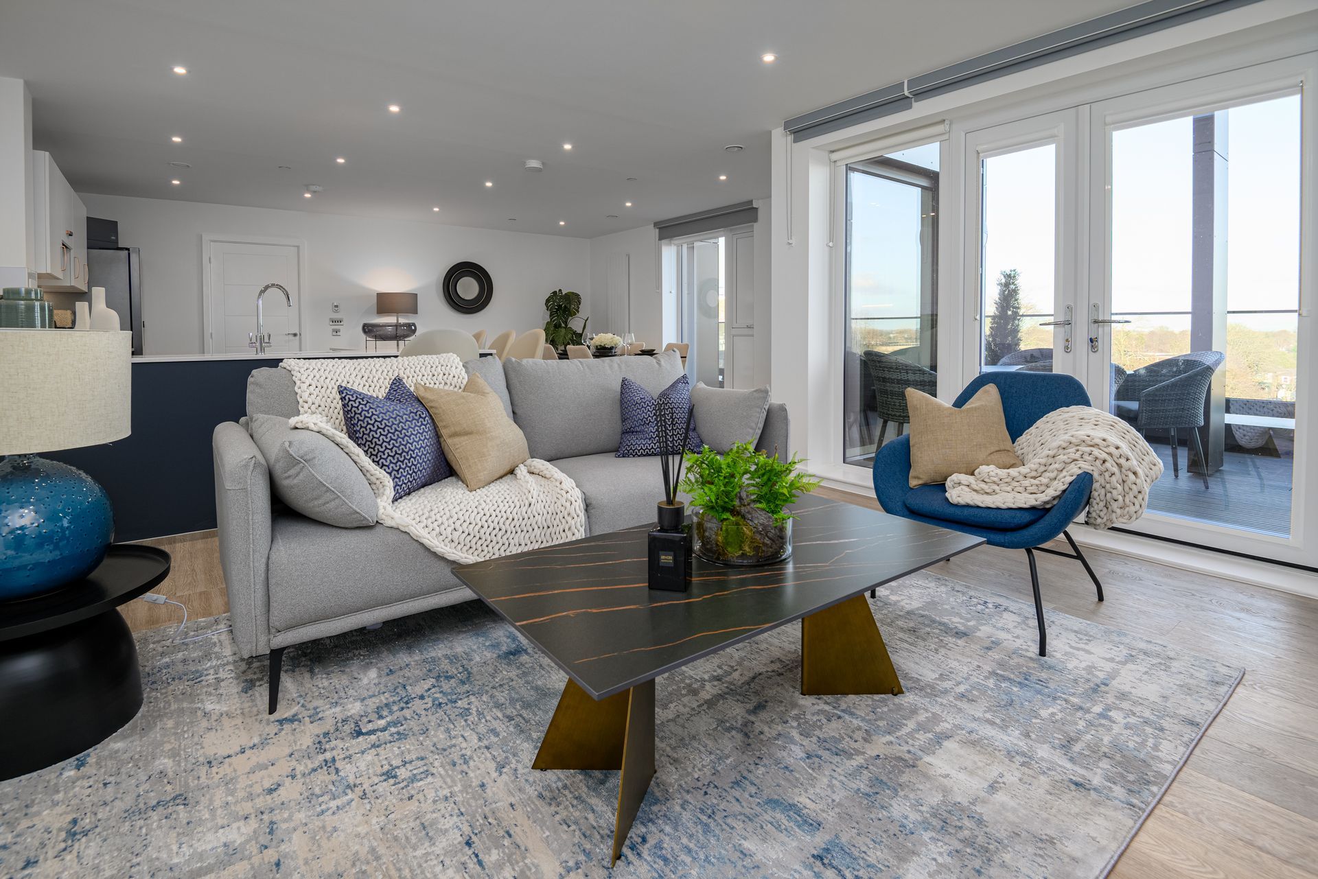 A living room with a couch , chair , coffee table and sliding glass doors at Walton Court.