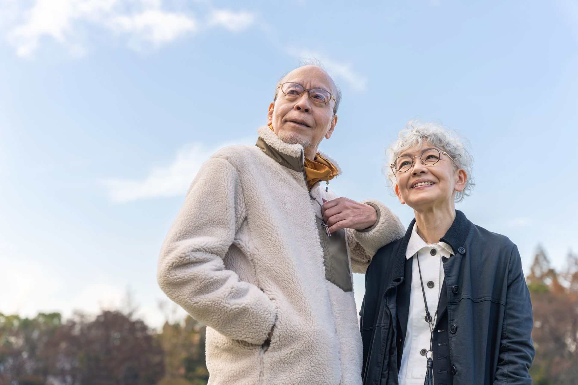 A man and a woman are standing next to each other in a park.