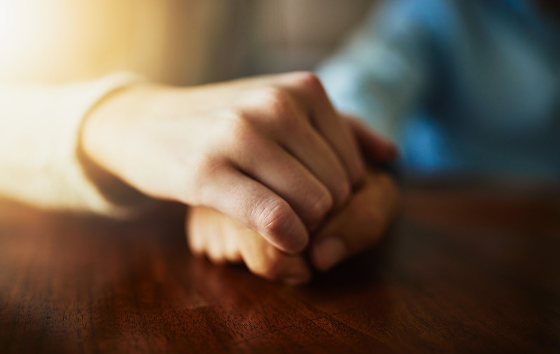 A person is holding another person 's hand while sitting at a table.