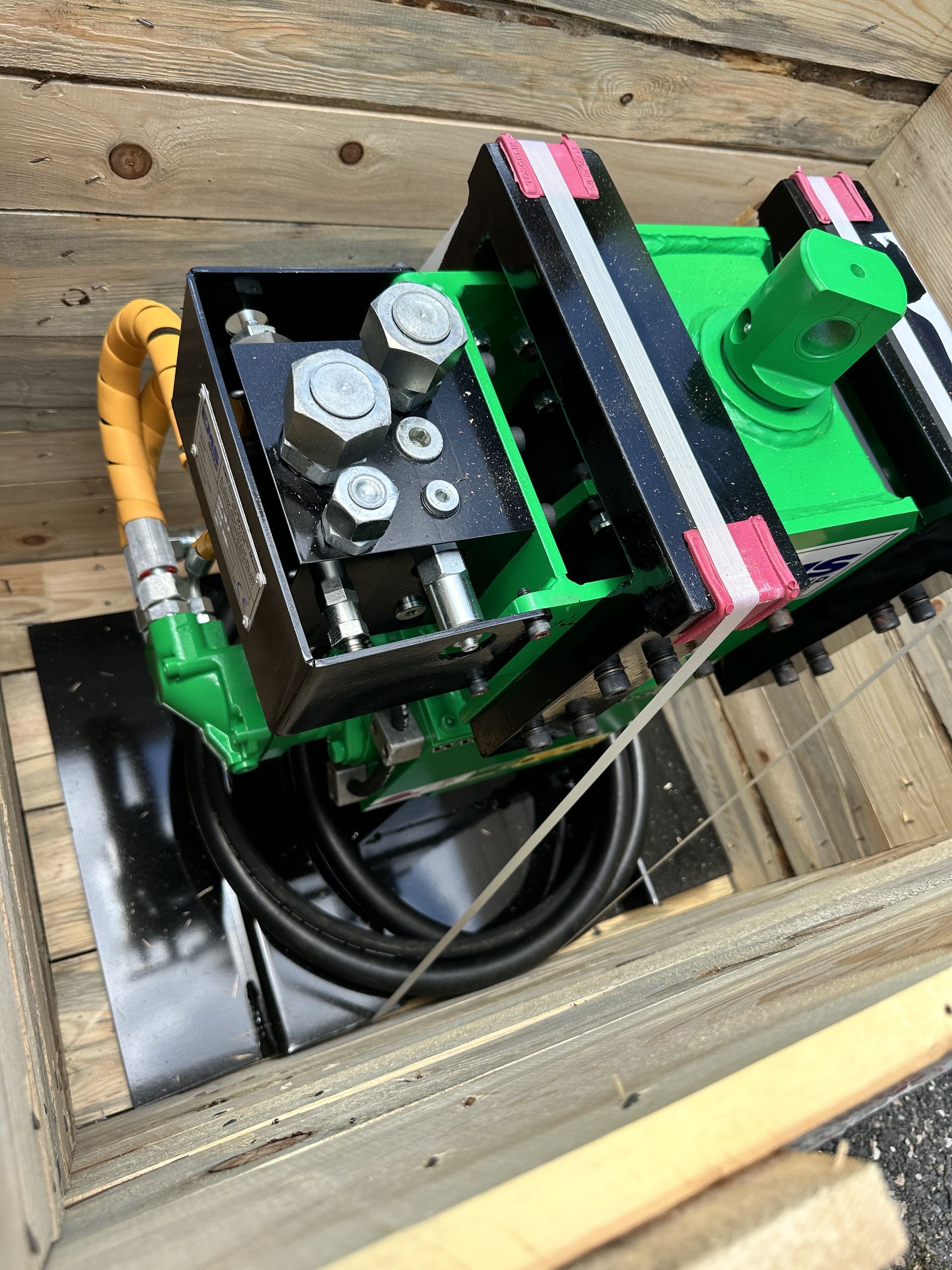 Green industrial machine inside a wooden crate, with black and metal components.