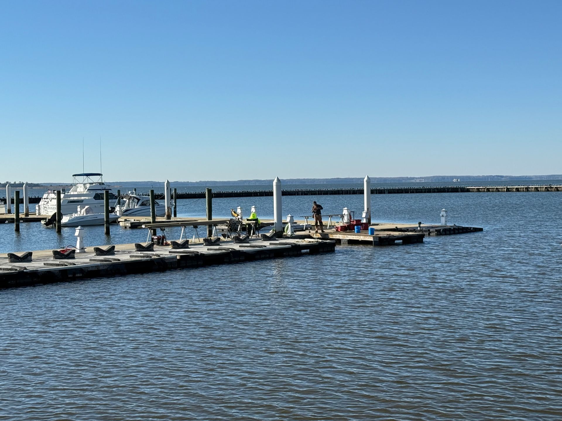 A boat dock with several boats in the water on a sunny day.