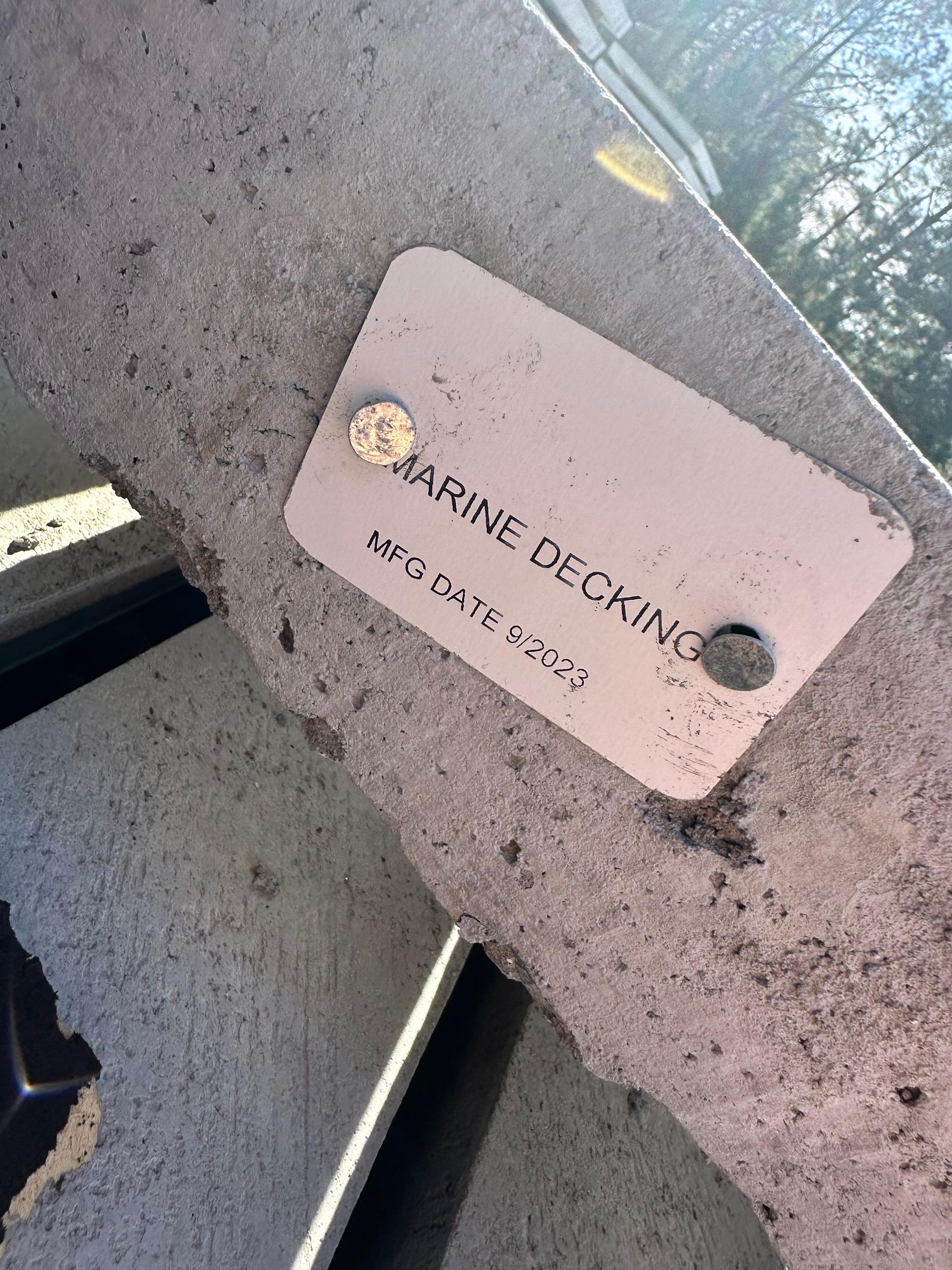 A gray metal tag on concrete reads 