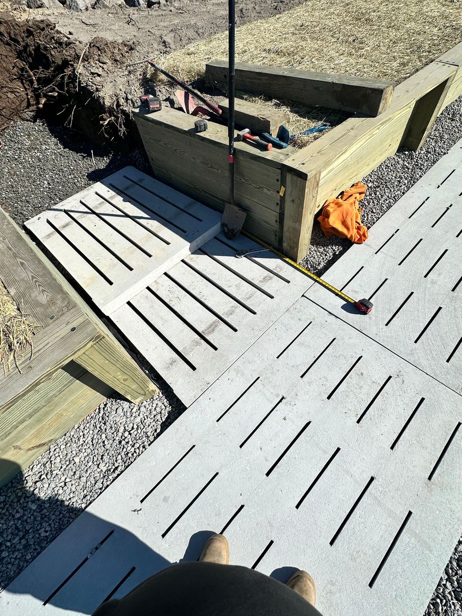 Concrete pavers with angled slots and construction materials on a worksite.