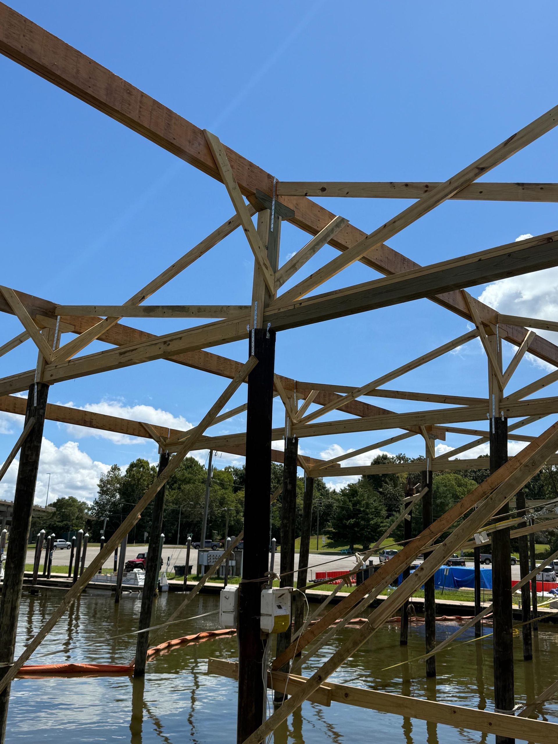 Wooden structure being built over water, blue sky background.