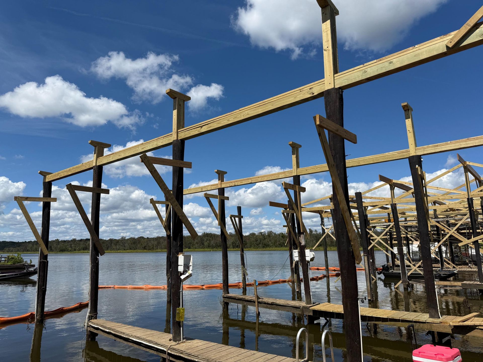 Wooden dock construction on a lake under a partly cloudy sky.