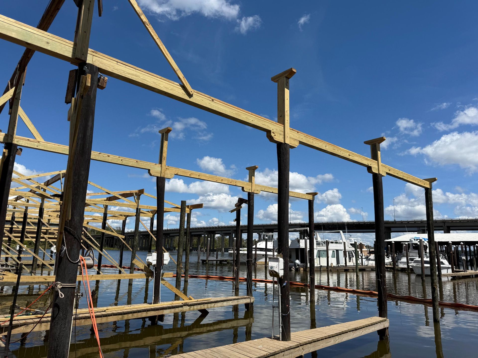Dock construction with wooden supports in water under a blue sky.