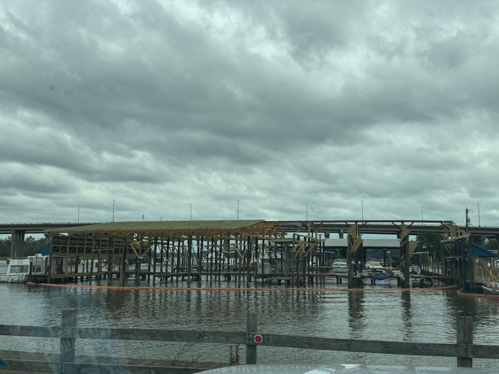 Construction over water, cloudy sky, wooden framework, orange barrier.