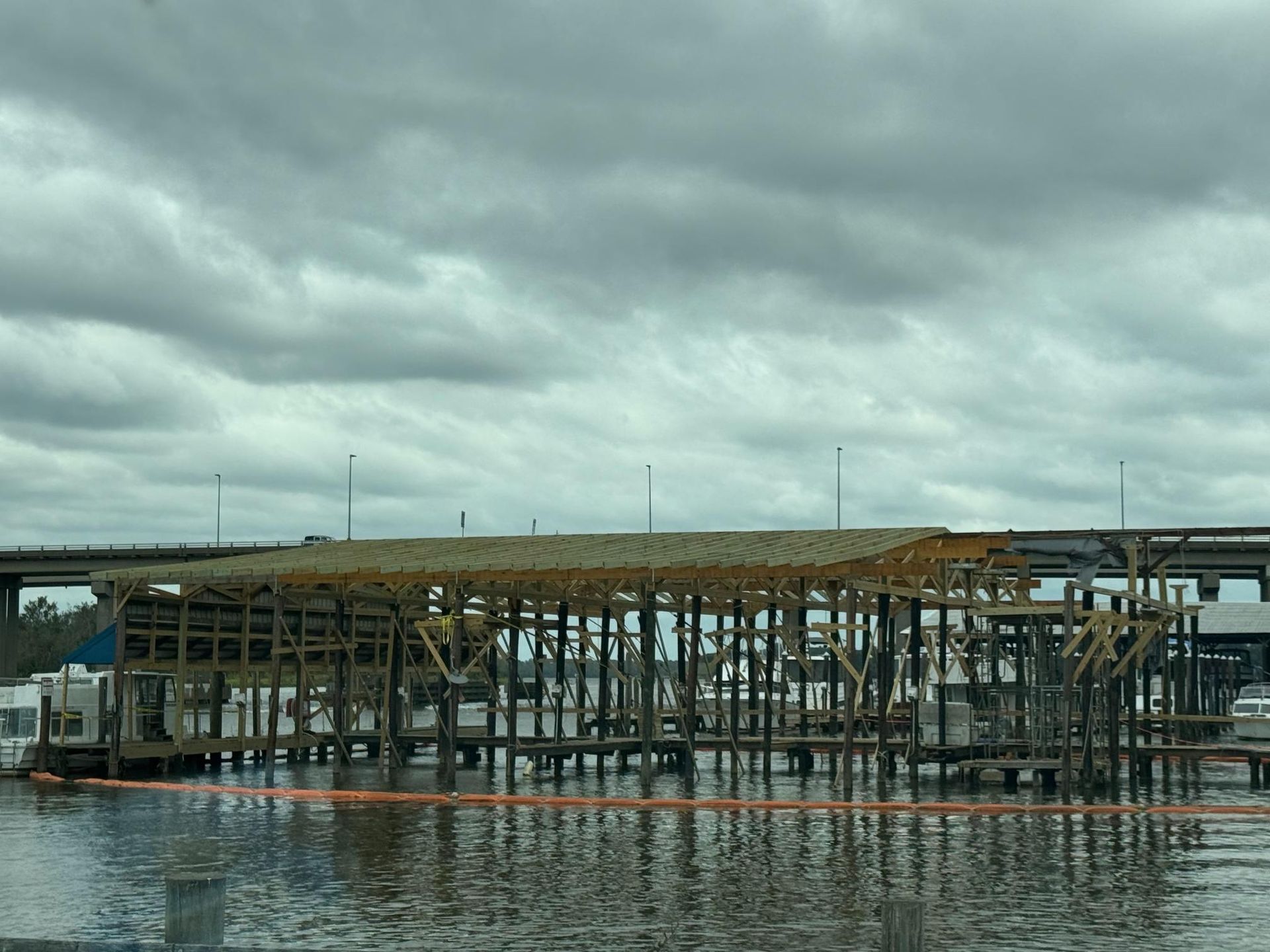 A wooden boat dock with a cloudy sky backdrop. The dock is built over water.