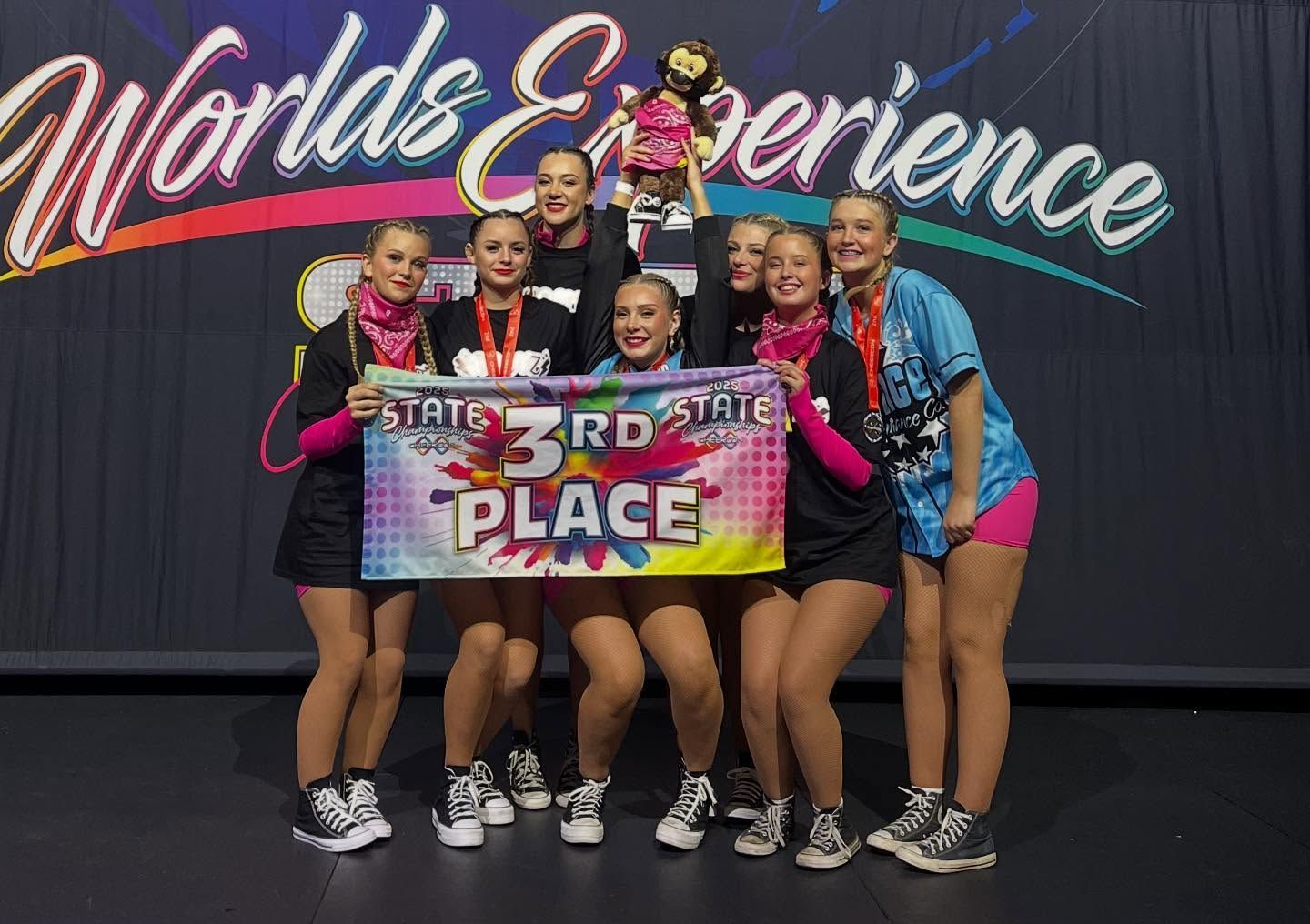 Dance Team Holding a Banner on a Stage With a Backdrop — iDance Performance Co In Medowie, NSW