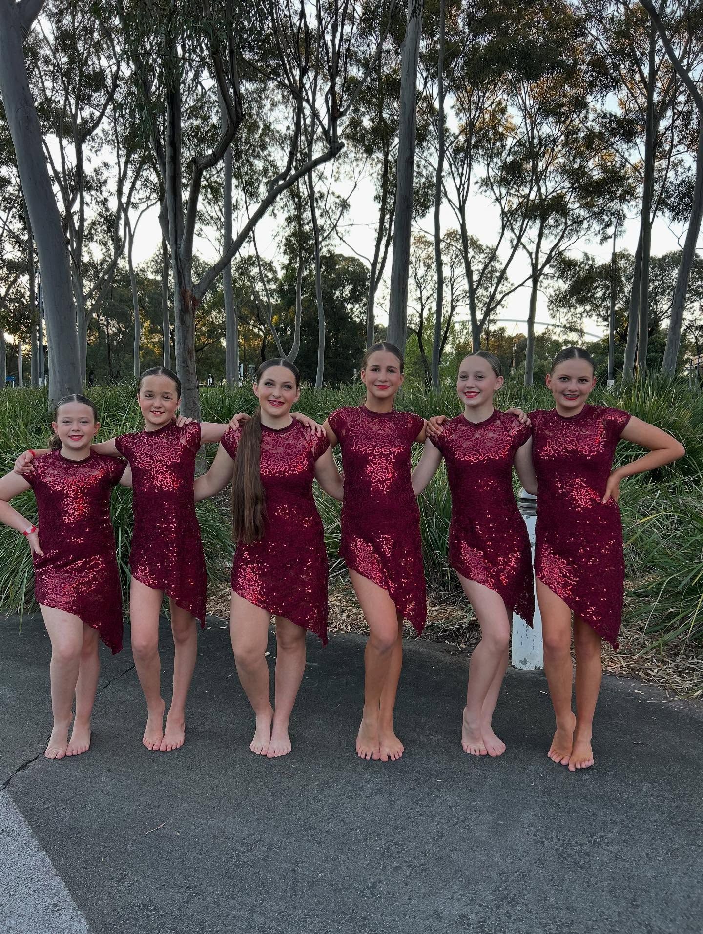 Six Dancers in Maroon Sequin Dresses Pose Outside, Arms Linked — iDance Performance Co In Medowie, NSW