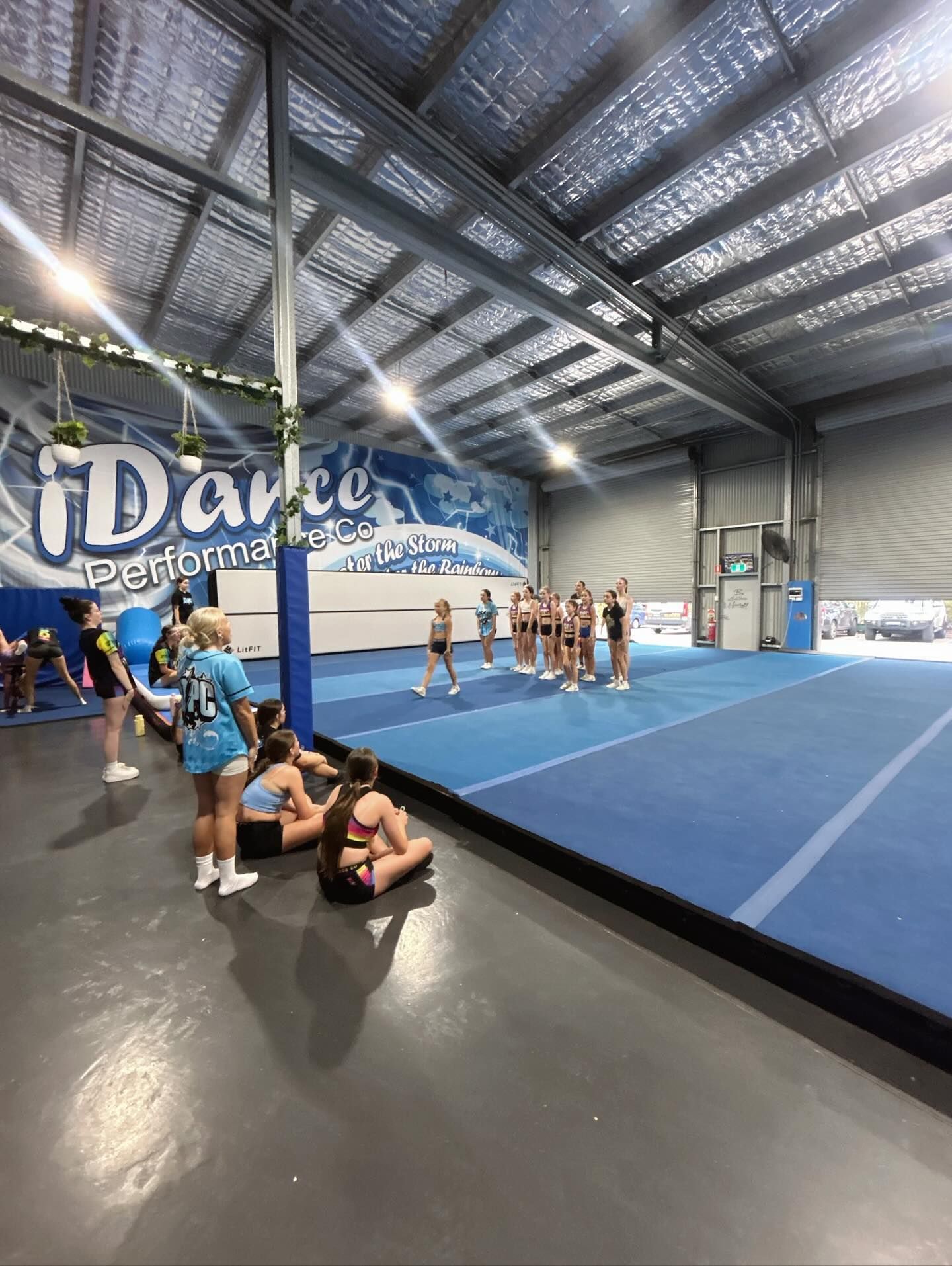 Cheerleading Practice in a Gym. Girls Stand on a Blue Mat, Others Watch — iDance Performance Co In Medowie, NSW