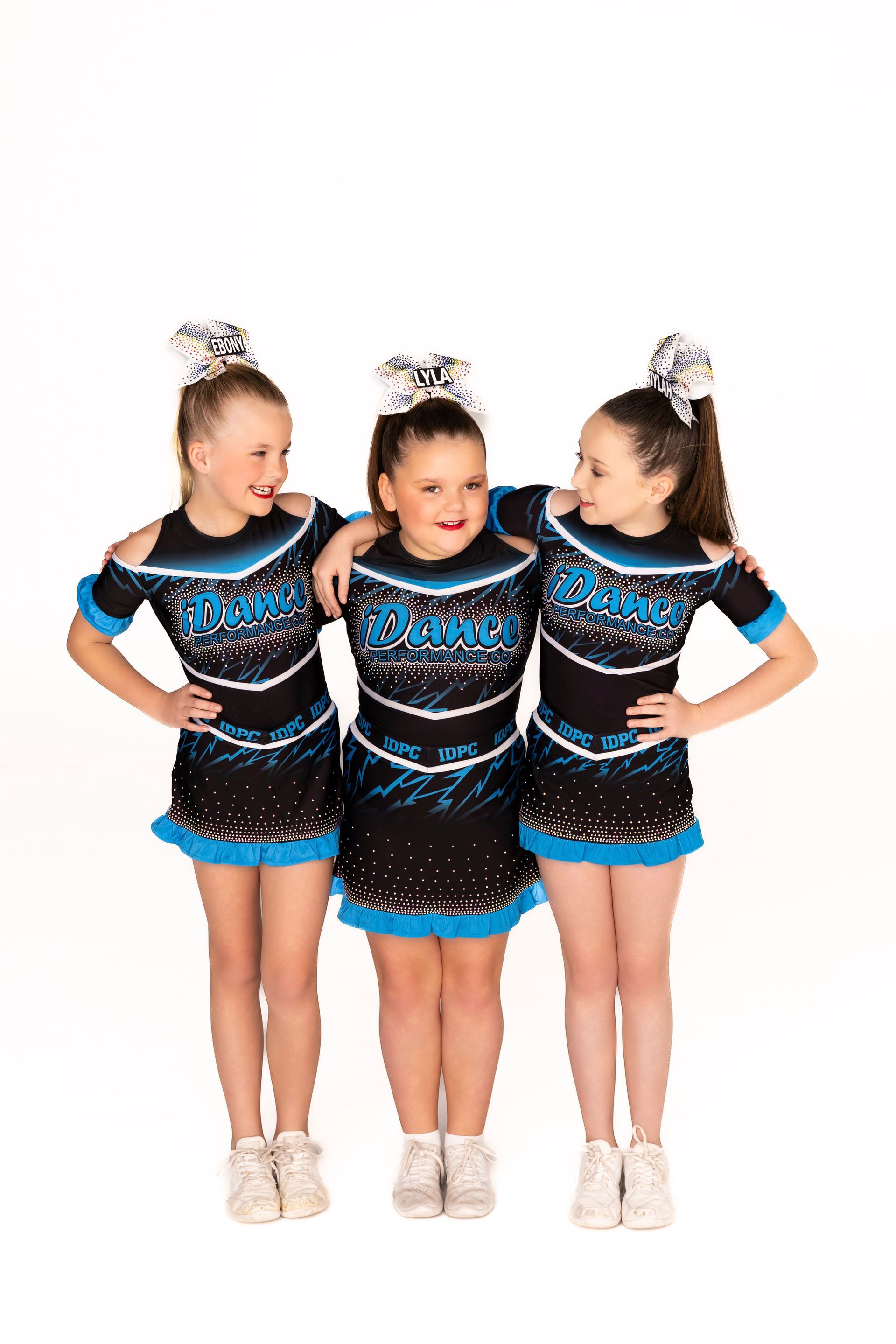 Three Cheerleaders in Black and Blue Uniforms Pose, Arms Around Each Other — iDance Performance Co In Medowie, NSW