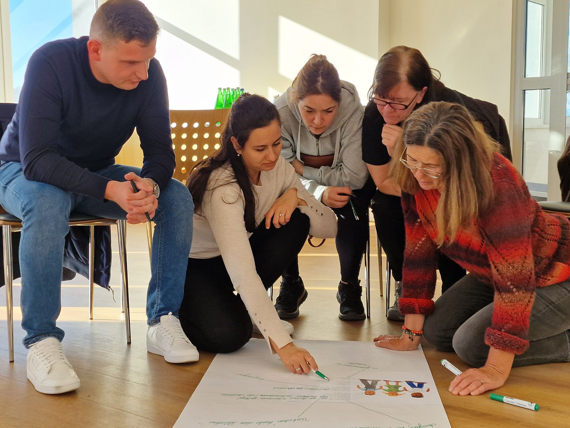 Eine Gruppe von Leuten betrachtet ein Stück Papier auf dem Boden.