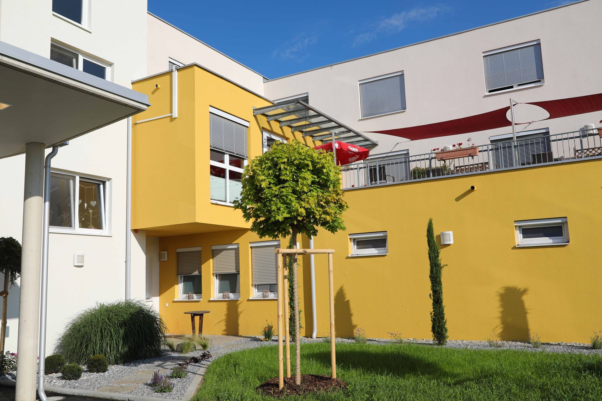 Ein gelb-weißes Gebäude mit einem Baum davor
