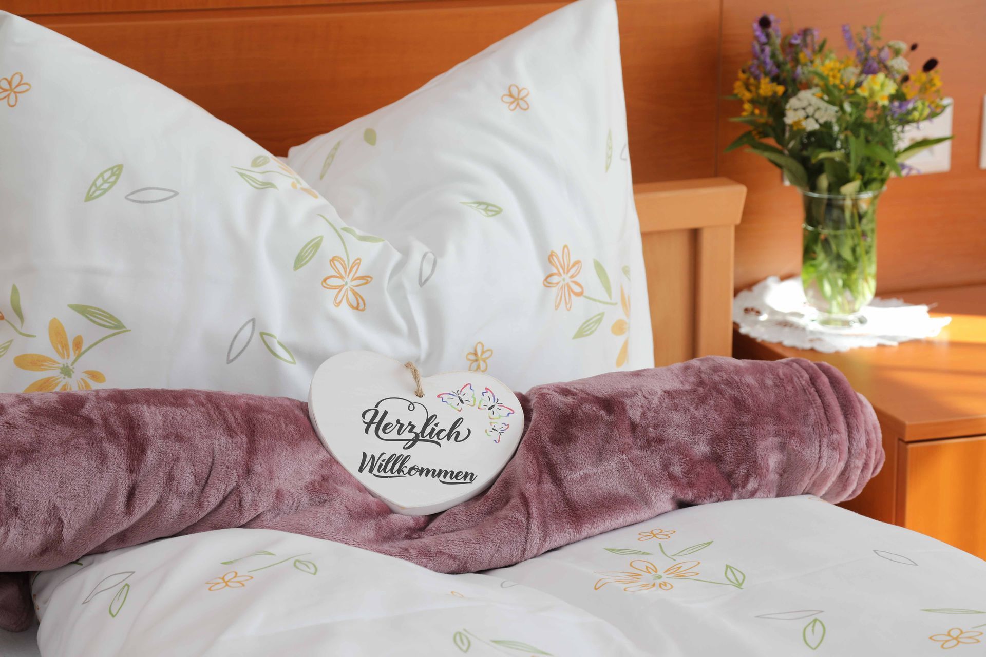 Ein Bett mit einem Schild darauf, auf dem steht: „Herzlich willkommen“