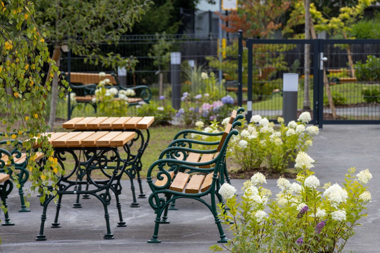 Eine Reihe von Bänken und Tischen in einem von Blumen umgebenen Park.