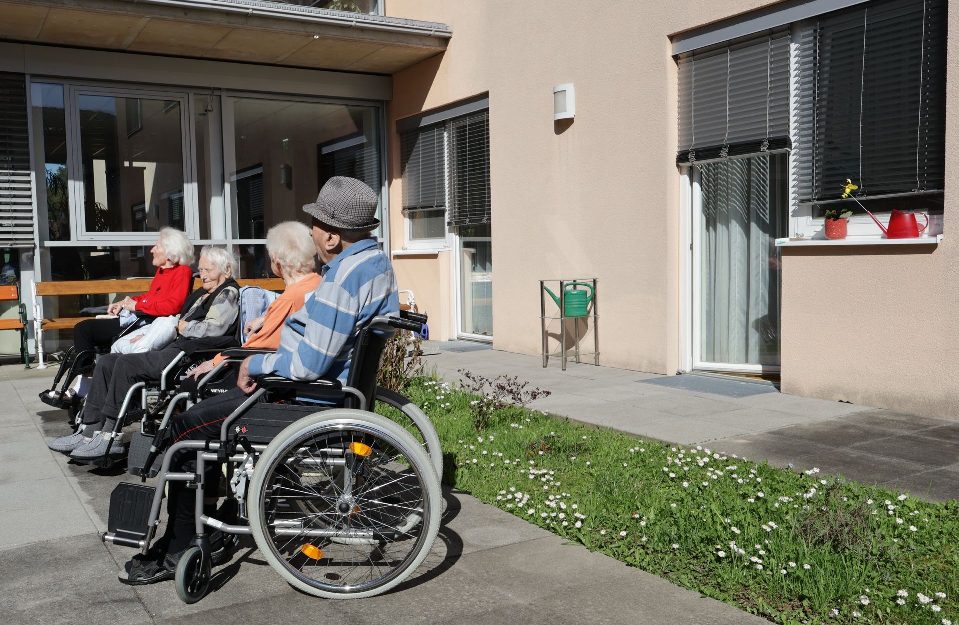 Eine Gruppe von Menschen im Rollstuhl sitzt vor einem Gebäude