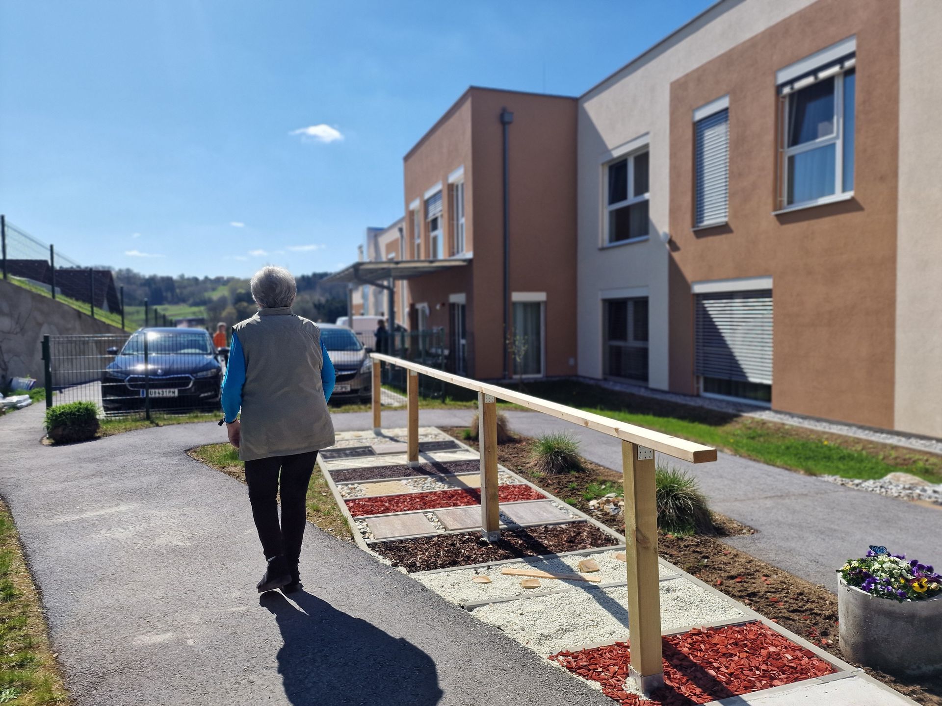 Eine Frau geht einen Weg vor einem Gebäude entlang