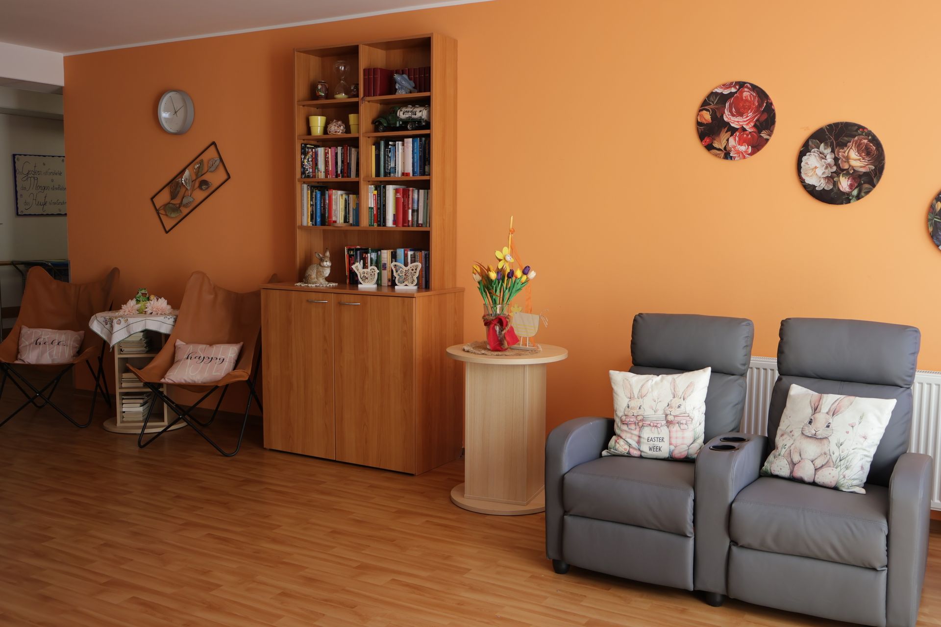Ein Wohnzimmer mit zwei Stühlen, einem Tisch und einem Bücherregal.