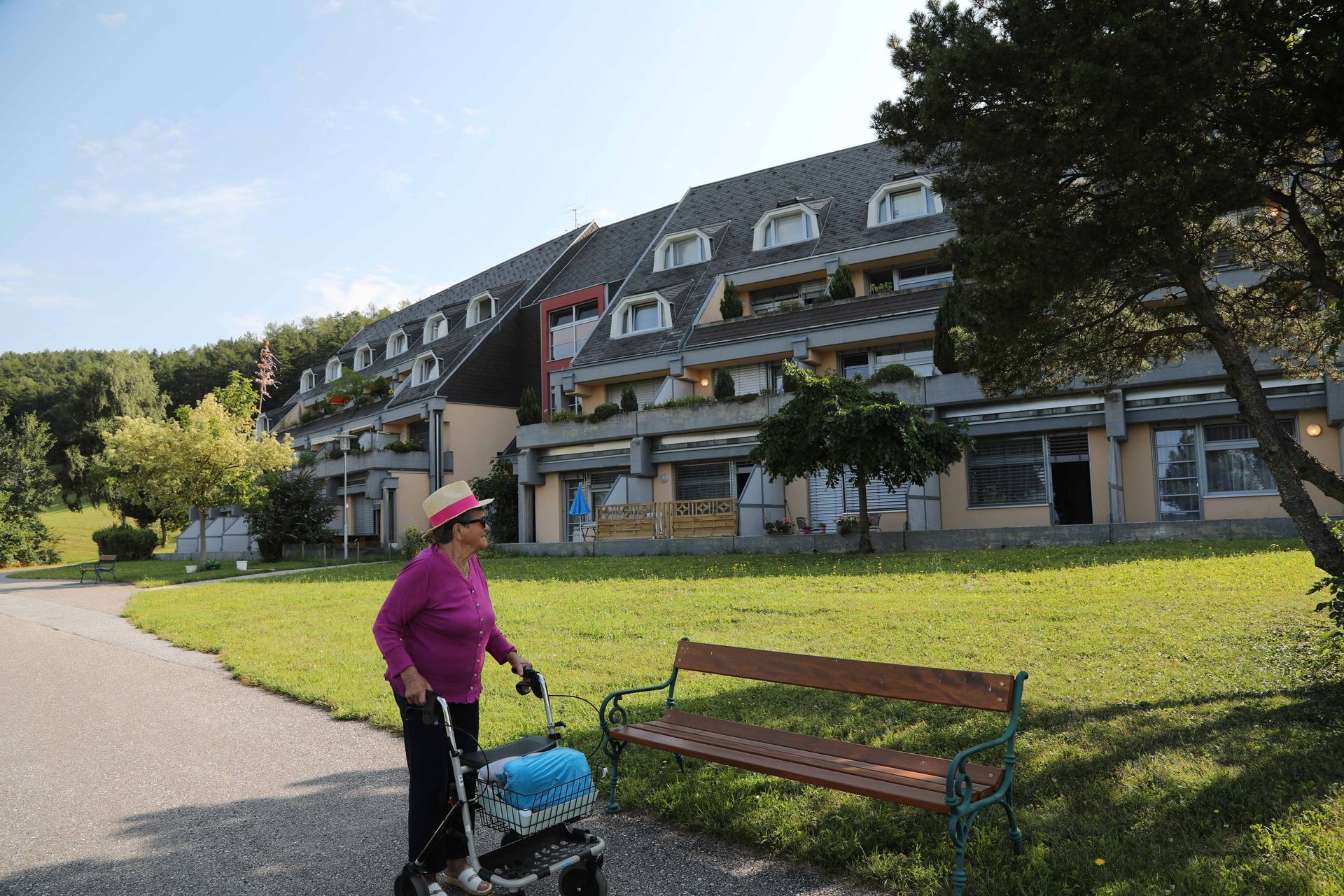 Eine Frau schiebt einen Kinderwagen einen Weg vor einem Gebäude entlang.