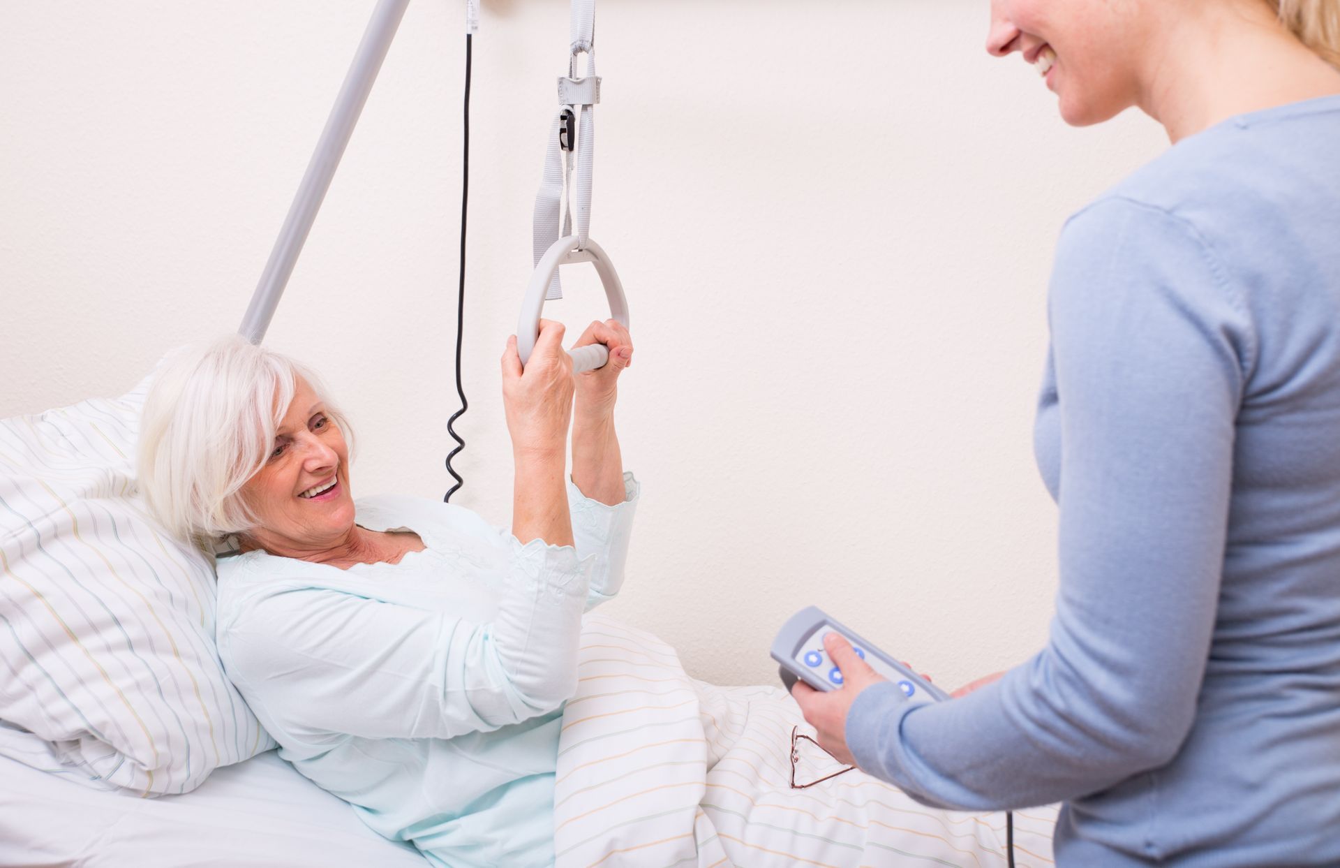 Eine Krankenschwester hilft einer älteren Frau in einem Krankenhausbett.