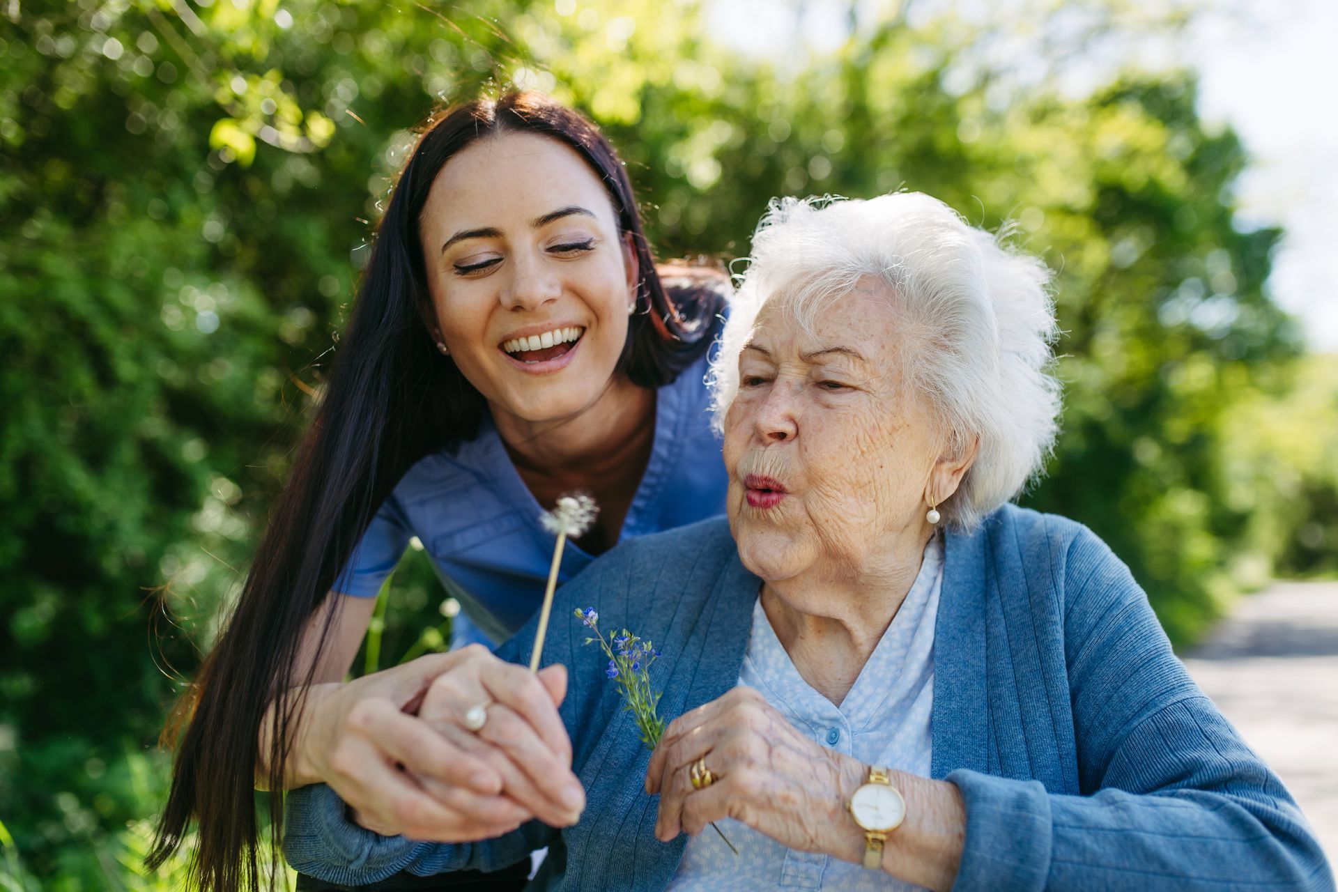 Eine junge Frau hält neben einer älteren Frau eine Blume.