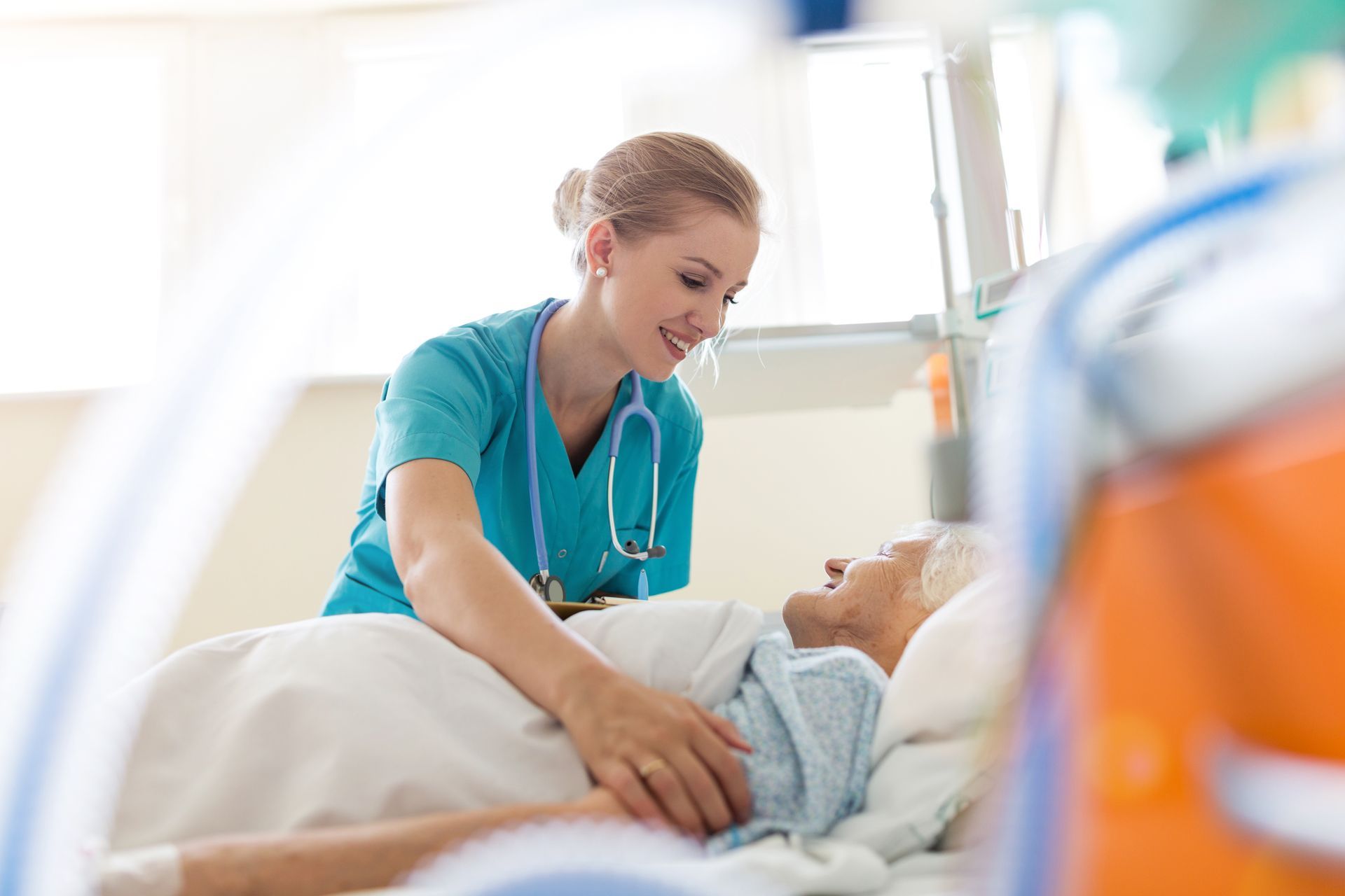 Eine Krankenschwester spricht mit einem Patienten in einem Krankenhausbett.