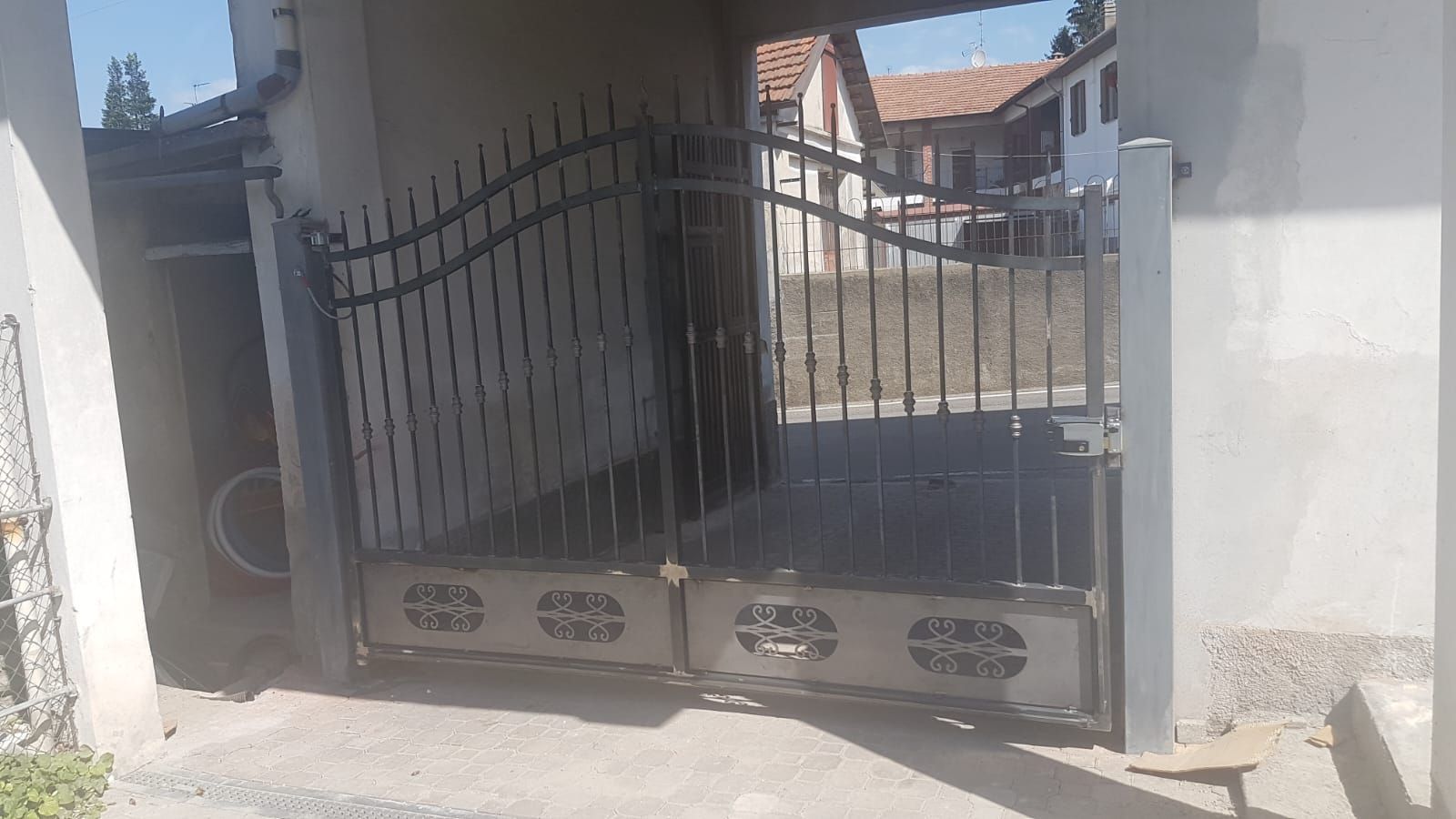 Un cancello di metallo si trova di fronte a un edificio bianco.