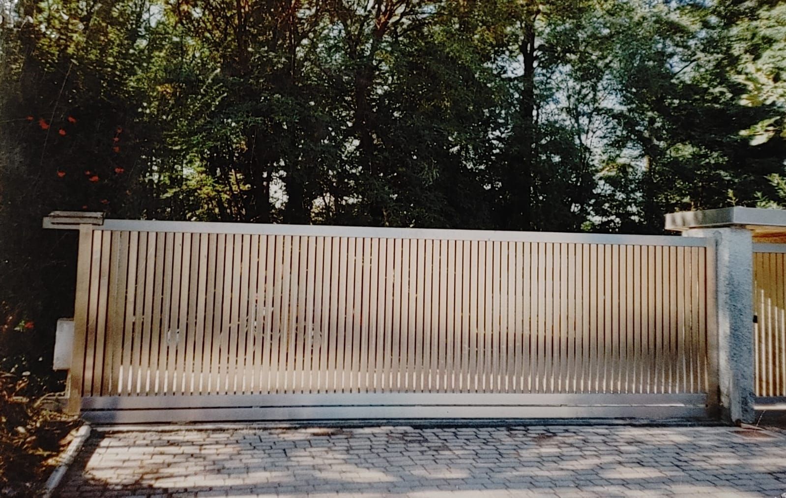 Un cancello scorrevole con una recinzione di legno dietro