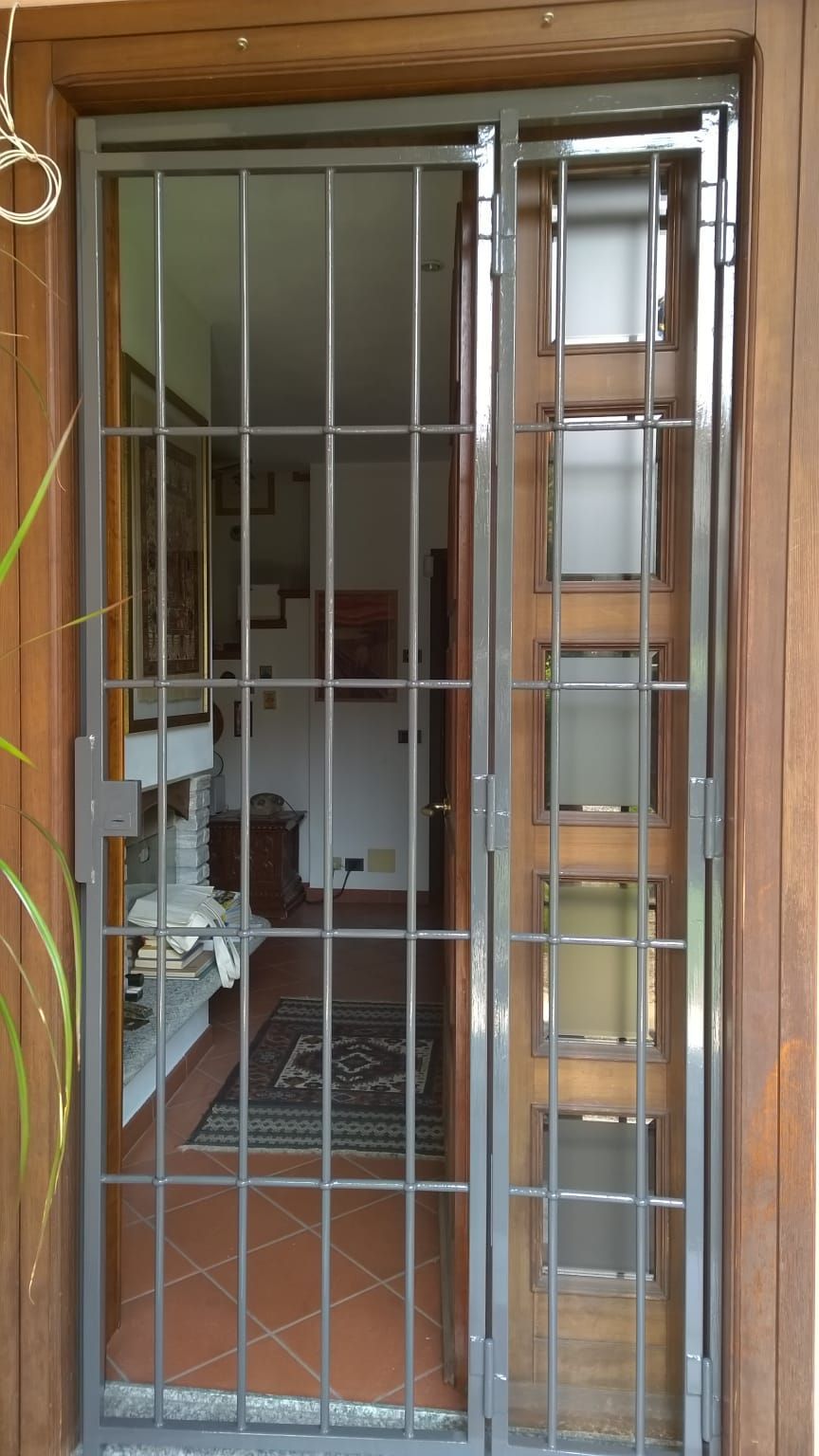 Una porta con una griglia metallica è aperta su un soggiorno
