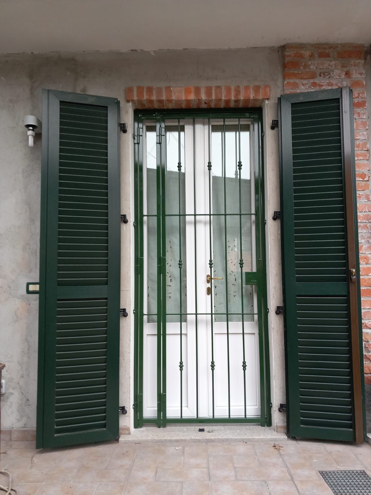 Una porta con persiane verdi e un cancello di metallo