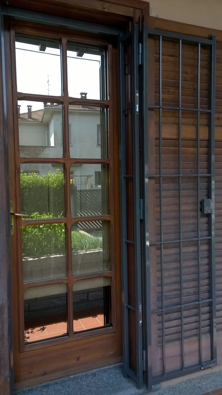 Una porta di legno con un cancello di metallo e delle persiane.