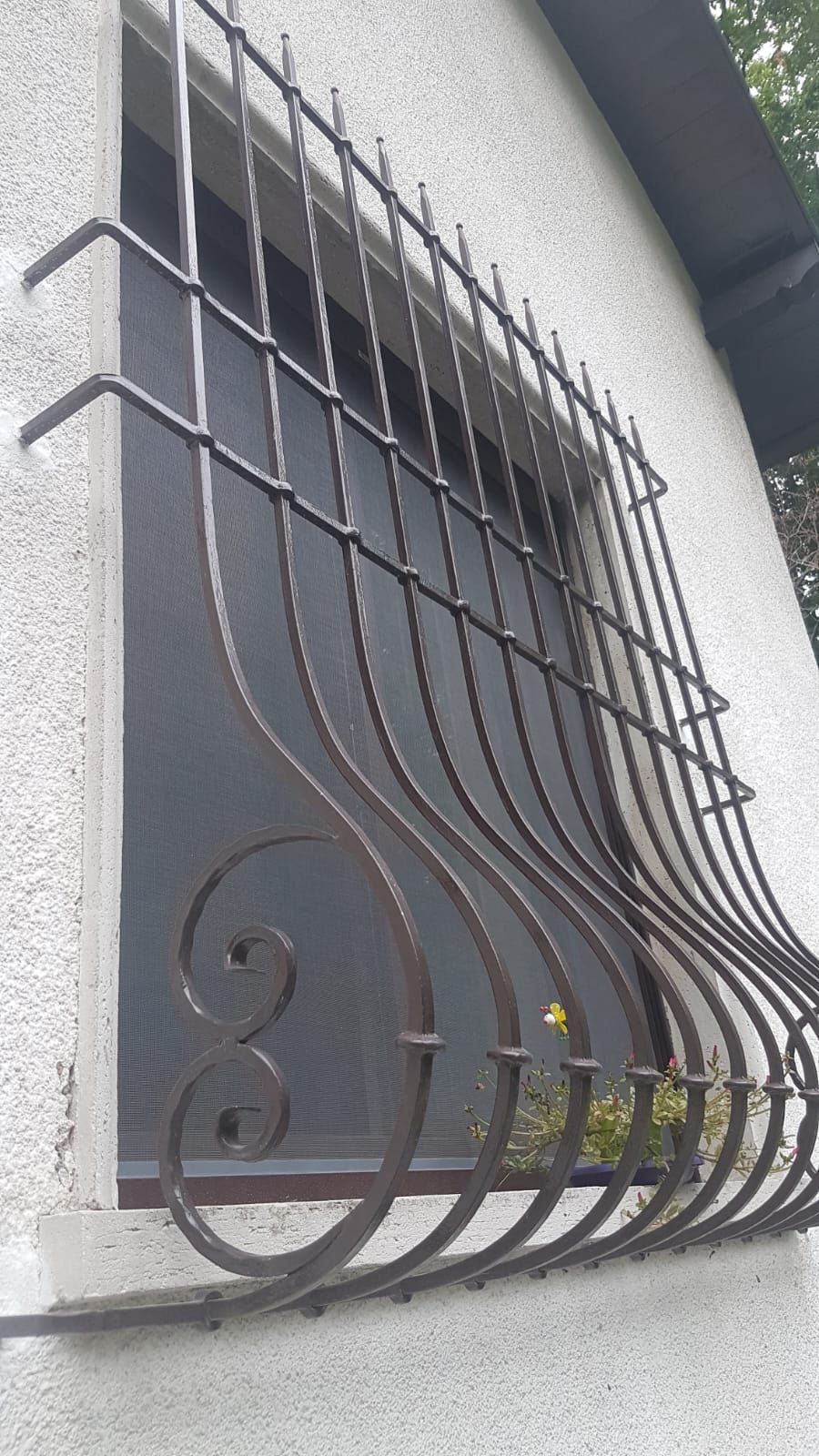 Una finestra con una grata in ferro battuto.