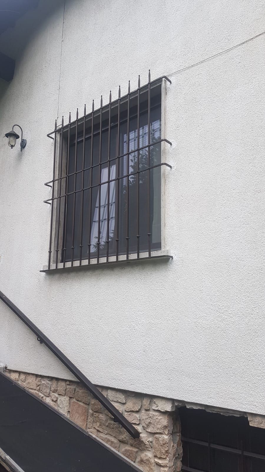 Una casa bianca con una finestra munita di sbarre.