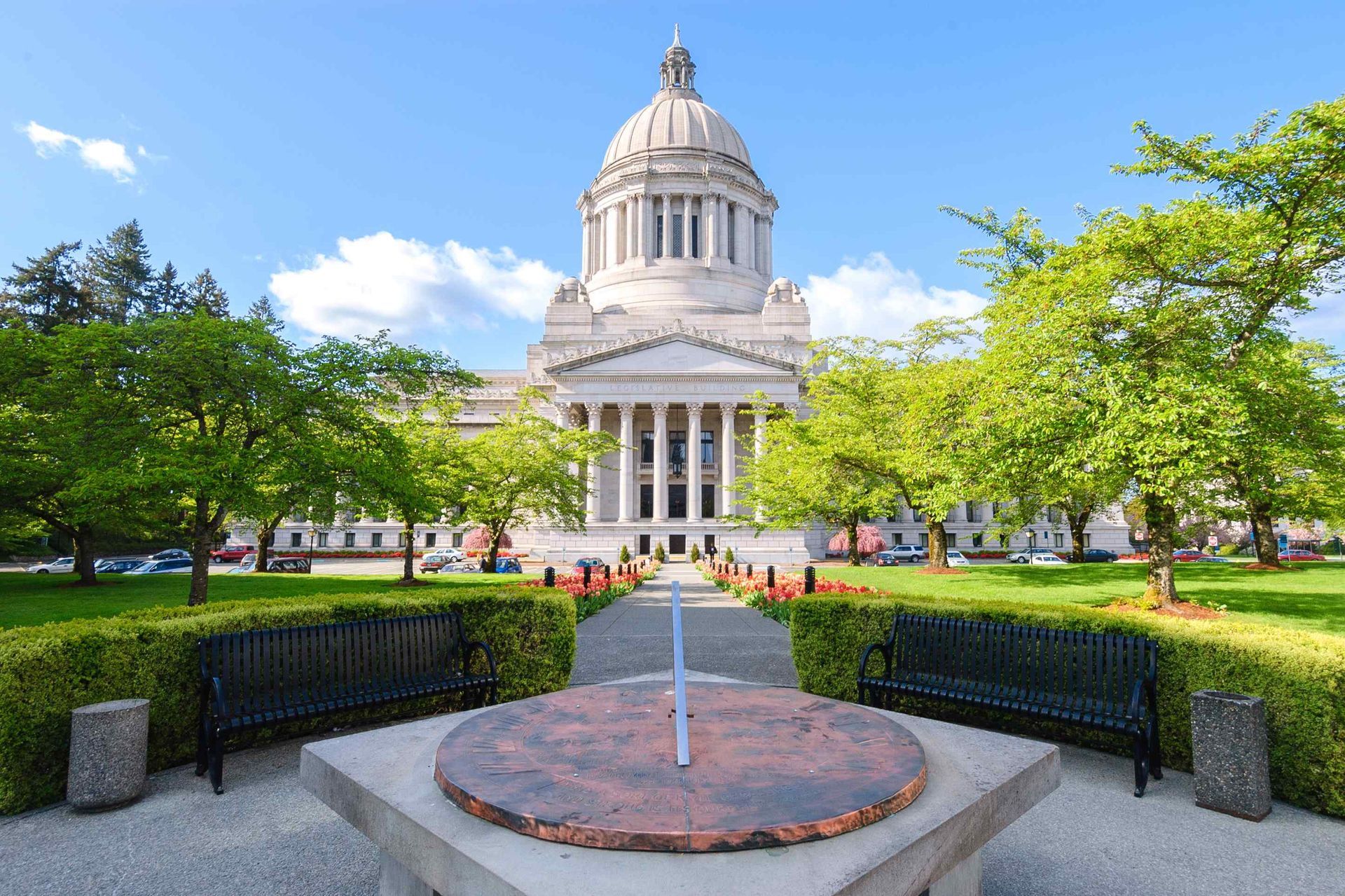 Washington State Capitol Building with a sundial in the foreground and green trees and grass.