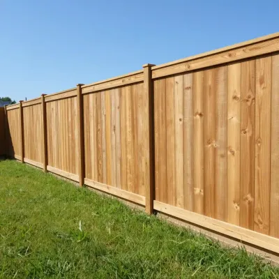 Wooden privacy fence along a green lawn under a clear blue sky