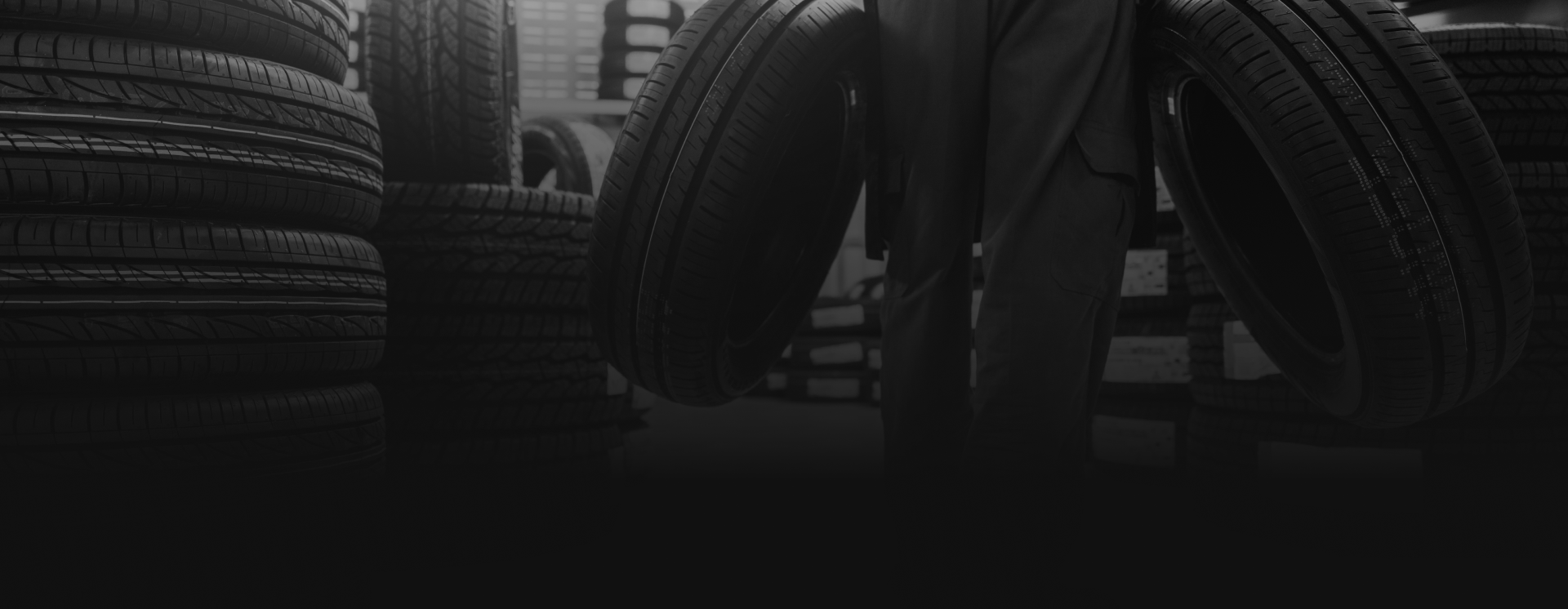 Tires stacked and leaning against each other inside a dimly lit garage. | Tires On Location