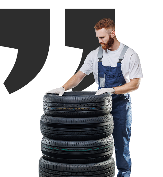 Mechanic in blue overalls and gloves stacking tires. | Tires On Location