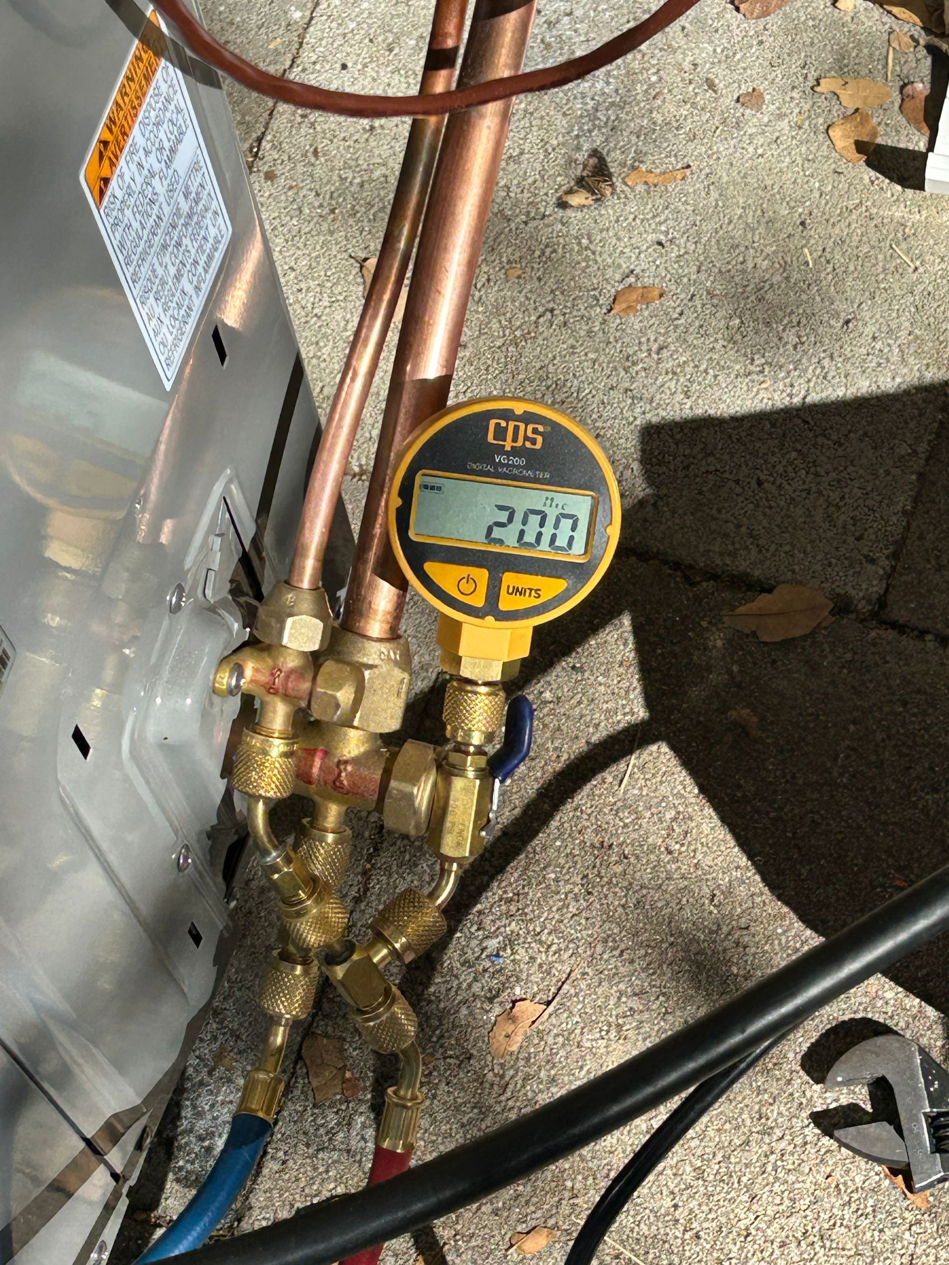 Yellow gauge reads 203 connected to an air conditioning unit's copper pipes.