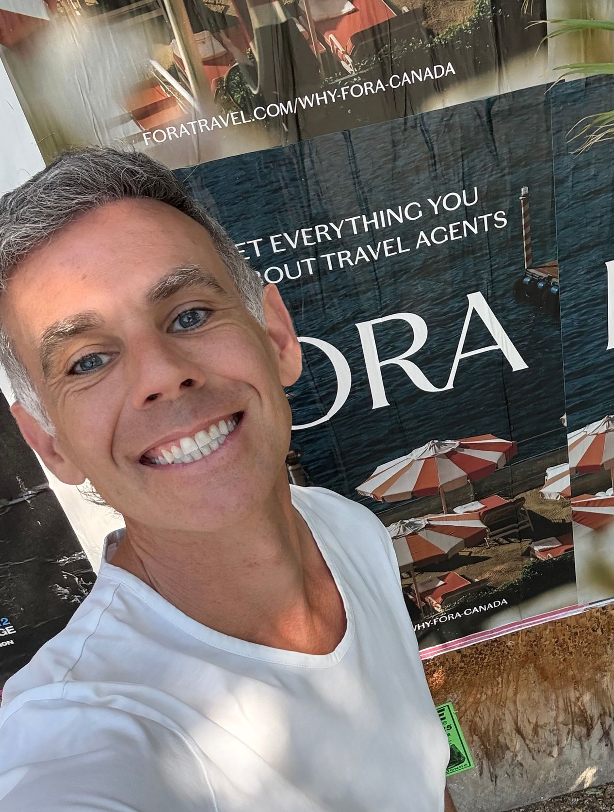 Woman in yellow beret and dress, looking through binoculars, lying on orange blanket against an orange wall.