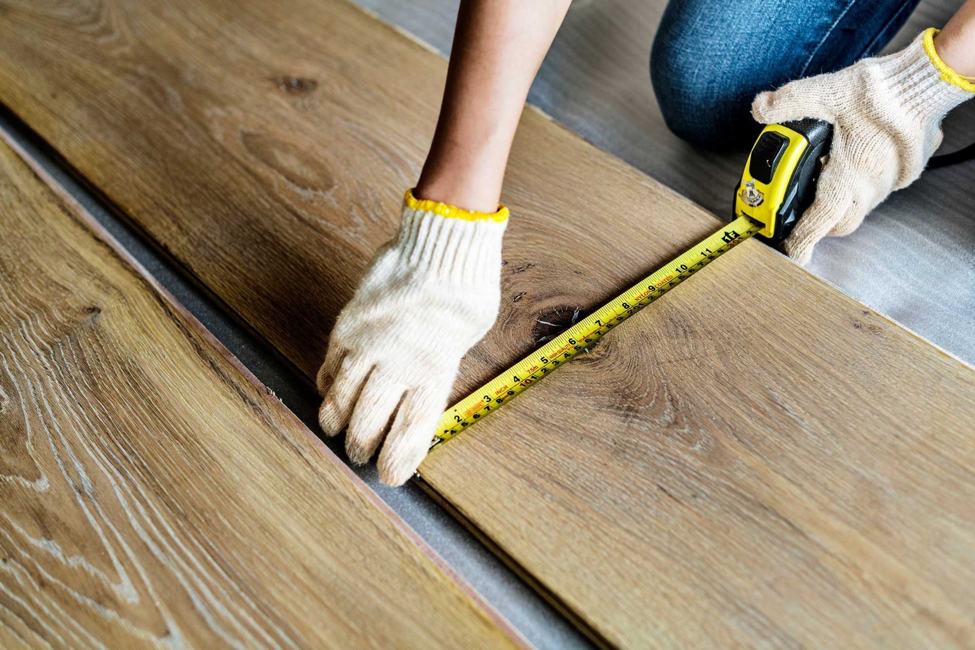 Professionally measuring wood planks during a hardwood flooring installation for a home renovation.